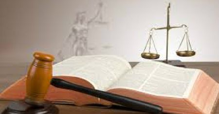 Libro de leyes abierto con mazo de juez y balanza de la justicia